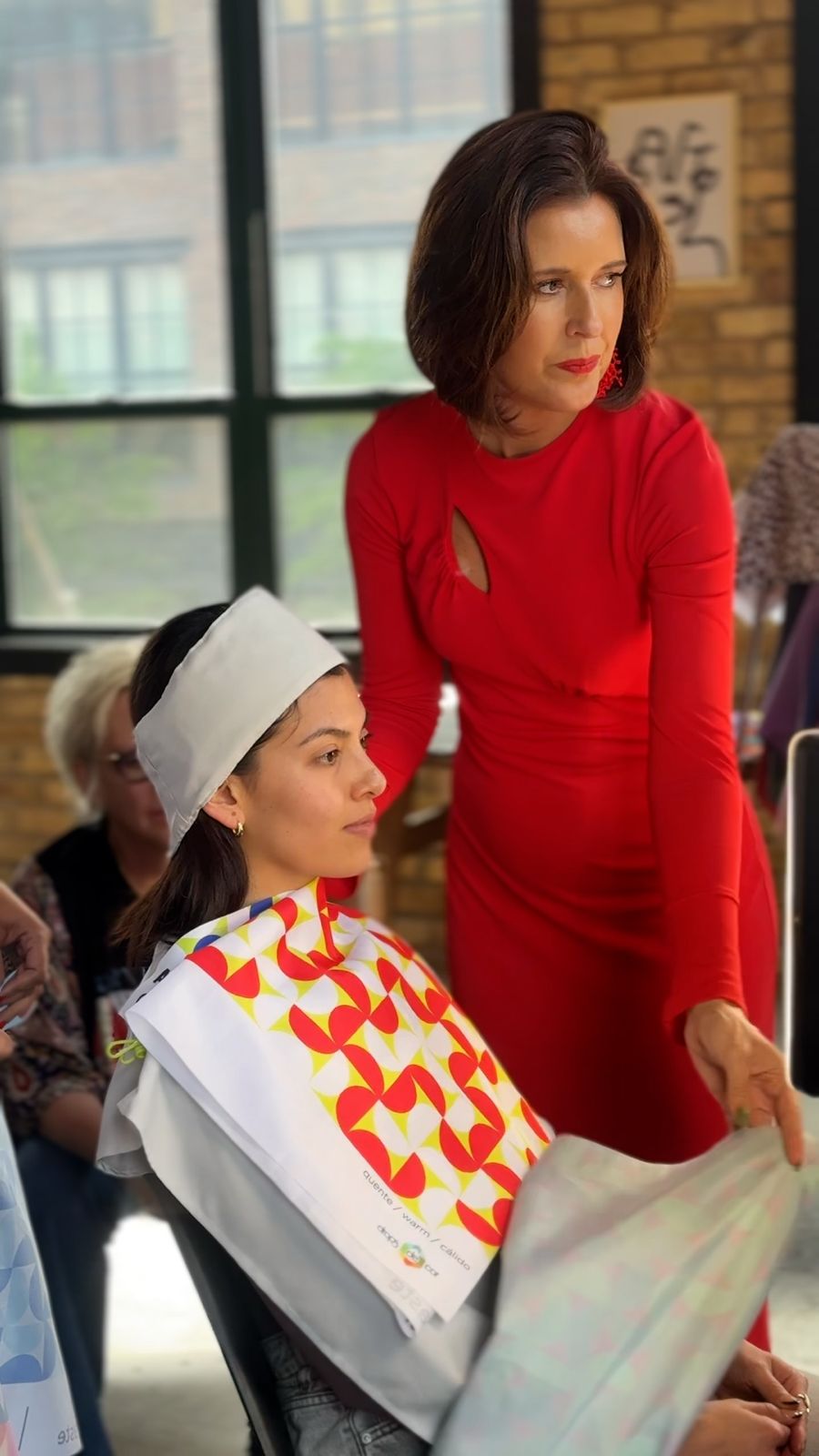 Sissa draping a student's client in a red-and-white printed drape